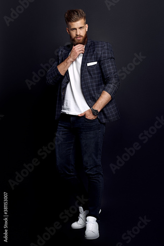 Confident and handsome. Full length of young man with ginger beard in smart-casual clothes looking at camera while posing against black background