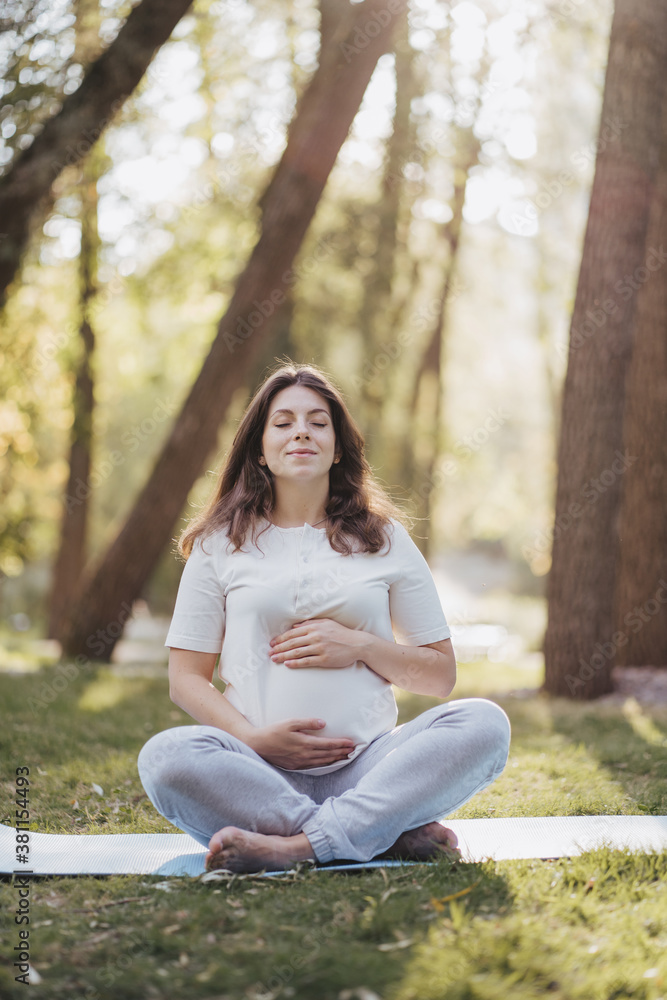 Pregnant woman sitting on the grass, meditating Pregnant woman sitting on the grass, meditating