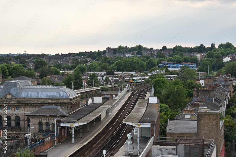 Looking down at the rail tracks and departing train at Peckham rail station