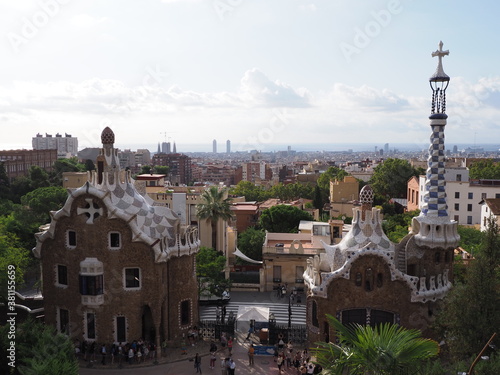 BARCELONA, SPAIN on SEPTEMBER 2019: Famous townscape of european city at Catalonia district and chimney of entrance building to Park Guell, cloudy blue sky in warm sunny summer day.