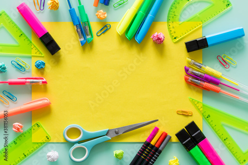 school and office items, colored pens, staples, markers, set squares, a blank yellow sheet of text in the center.