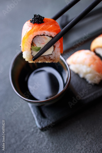 Chopsticks taking salmon maki roll from plate