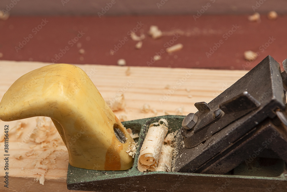 wood processing tools, retro hand planer, Board and shavings on the workbench in the mini-workshop. Copy space. wood processing tools, retro hand planer, Board and shavings on the workbench in the mini-workshop. Copy space.