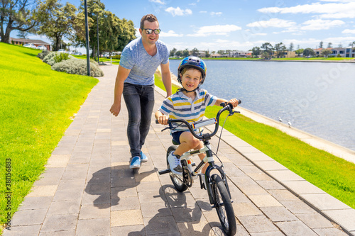 Father teaching his son to ride a bike and having fun together at the park