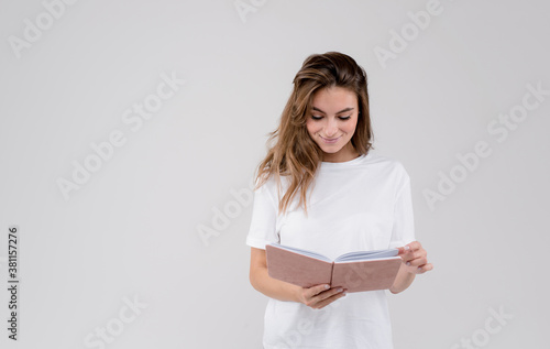 Image of beautiful brunettewoman wearing white t-shirt making notes in diary book isolated over white background photo