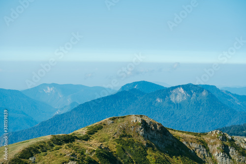 natural wallpaper with high mountains in fog and green hill