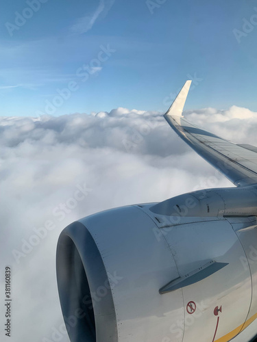 View of pompous clouds from the top of a plane. Window and wing of the plane.