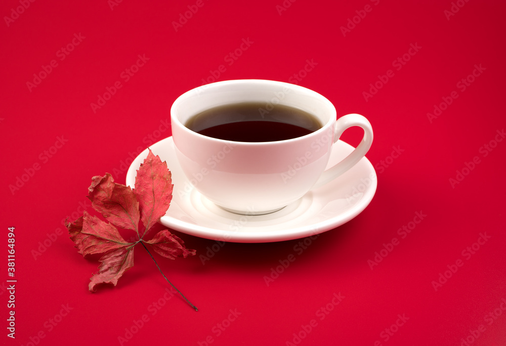 Autumn background with a Cup of herbal tea and a red leaf on a red background. The concept of an autumn greeting card, proper nutrition. Autumn background with a Cup of herbal tea and a red leaf on a red background. The concept of an autumn greeting card, proper nutrition.