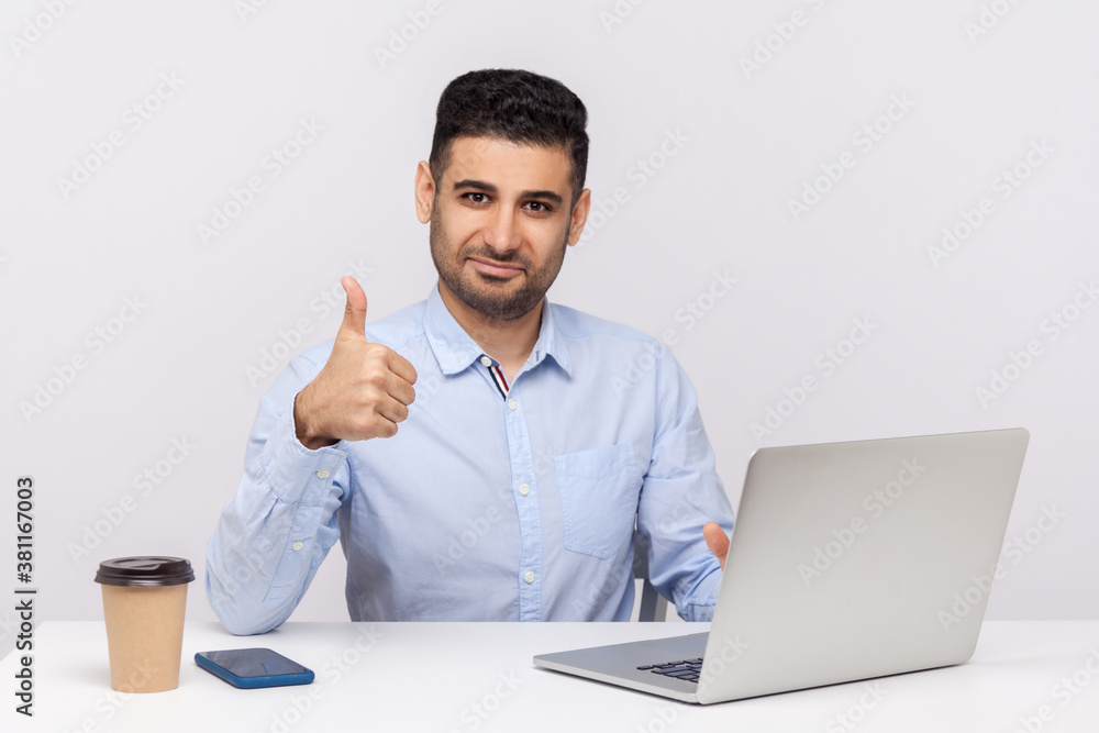 Well done, good job! Happy elegant businessman sitting office workplace, showing thumbs up, like gesture, satisfied with excellent business result. indoor studio shot isolated on white background Well done, good job! Happy elegant businessman sitting office workplace, showing thumbs up, like gesture, satisfied with excellent business result. indoor studio shot isolated on white background
