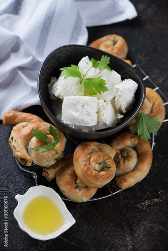 Greek spiral pies stuffed with spinach and feta cheese, vertical shot on a dark brown stone surface, selective focus