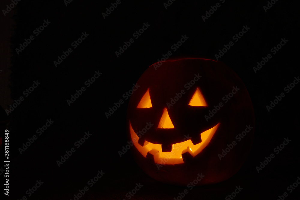 Halloween pumpkin smile and scary eyes for party night. Close up view of scary Halloween pumpkin with eyes glowing inside at black background. Selective focus Halloween pumpkin smile and scary eyes for party night. Close up view of scary Halloween pumpkin with eyes glowing inside at black background. Selective focus