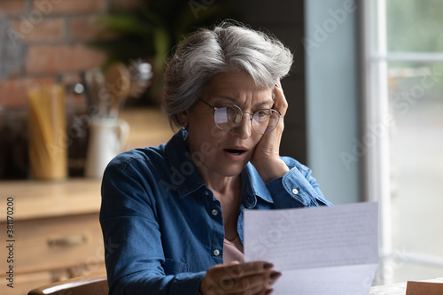 Photos Unhappy mature Caucasian 60s woman in glasses read post paper letter shocked by bad news