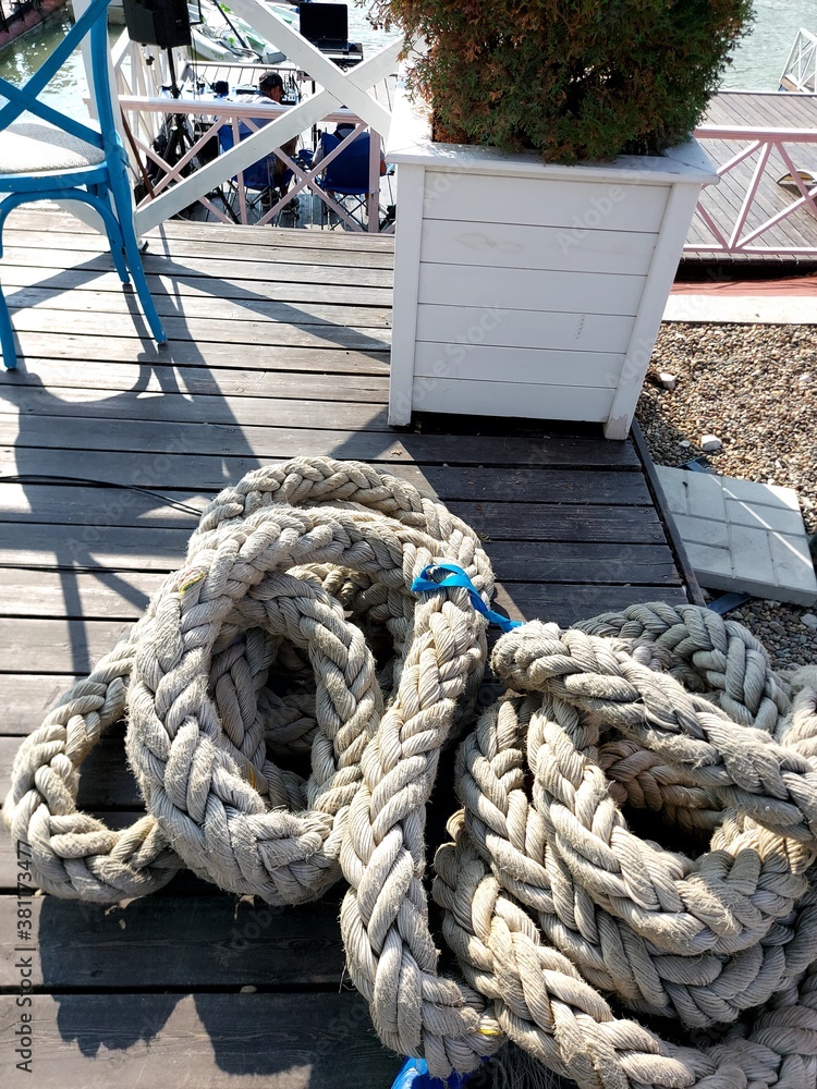 Wooden furniture on the cafe veranda and mooring rope. The sailing competition. Veranda with water view .