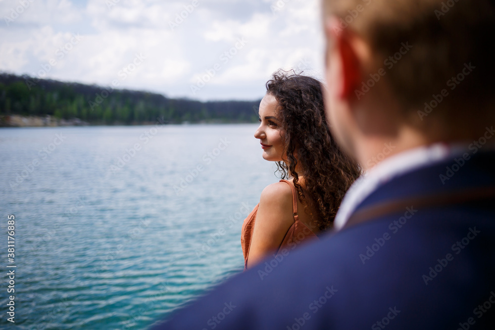 Couple in love near the water on a wooden bridge. Atmospheric couple. Life style. Girl with long curly hair smiles and rejoices
