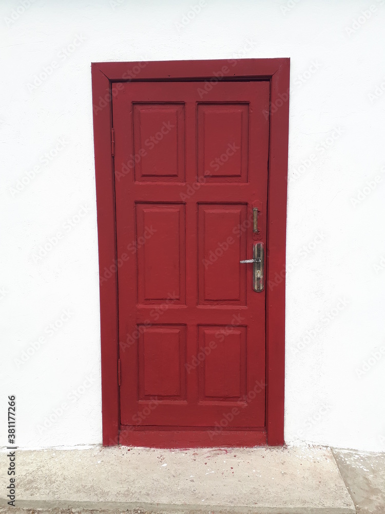A wooden door painted red against a white wall. A wooden door painted red against a white wall.