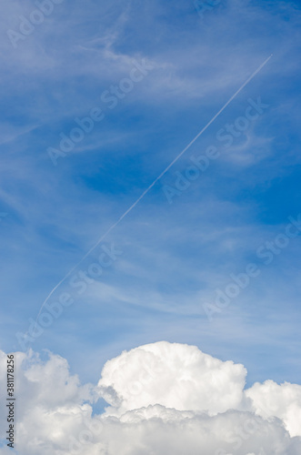Blue sky and contrail above white cloud
