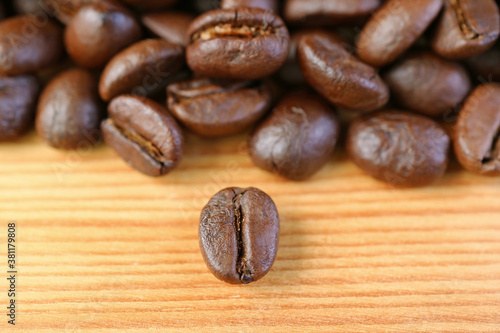 Closeup a Robusta Roasted Coffee Bean with Blurry Coffee Beans Pile in the Backdrop