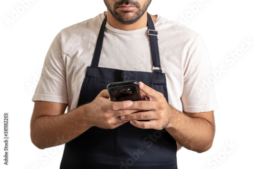 Young chef with black apron using a mobile on white background. © Rawf8