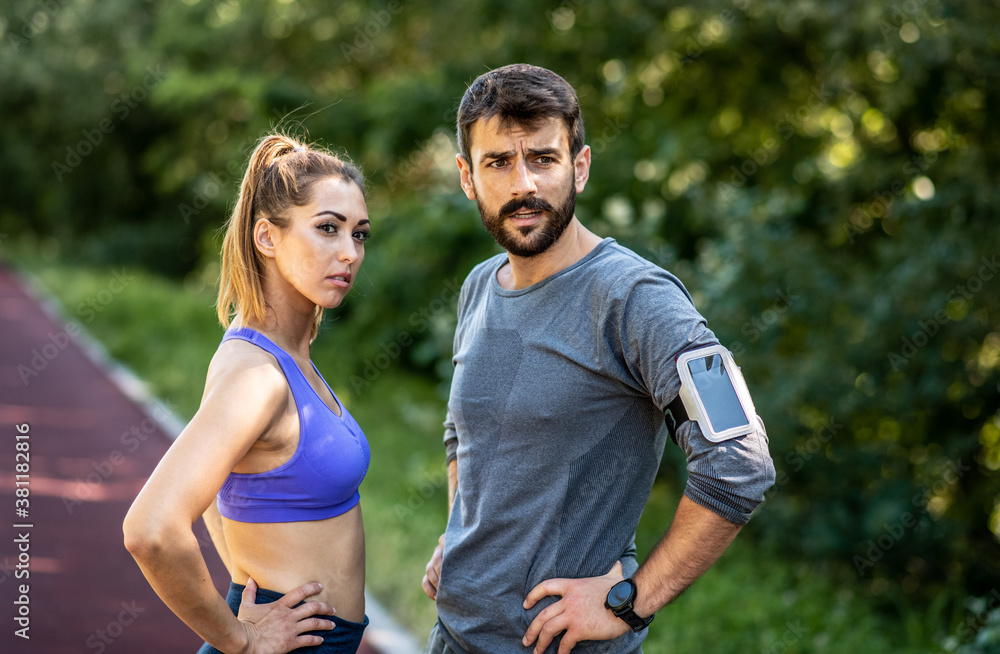 The young couple stands on the treadmill with serious looks and prepares themselves for training The young couple stands on the treadmill with serious looks and prepares themselves for training