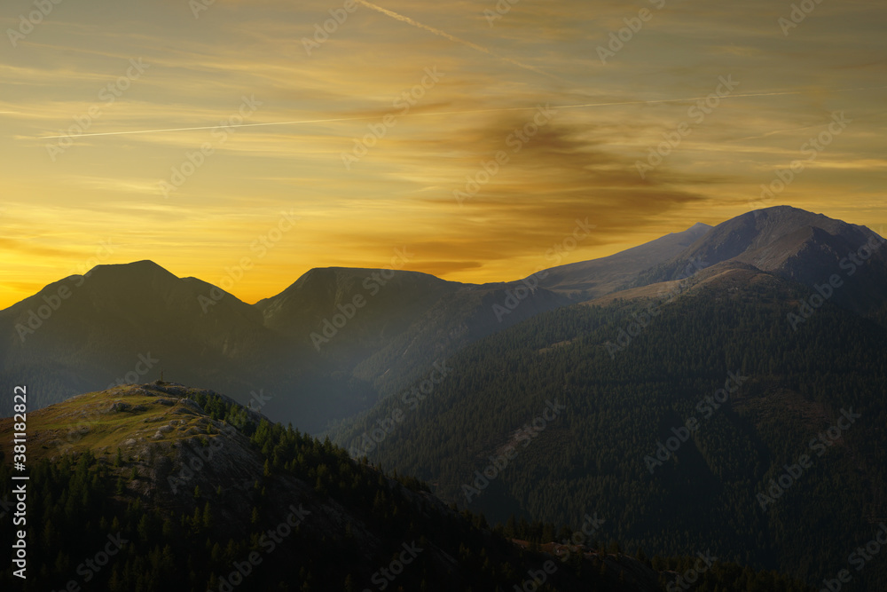 Berg mit Gipfelkreuz im Sonnenuntergang