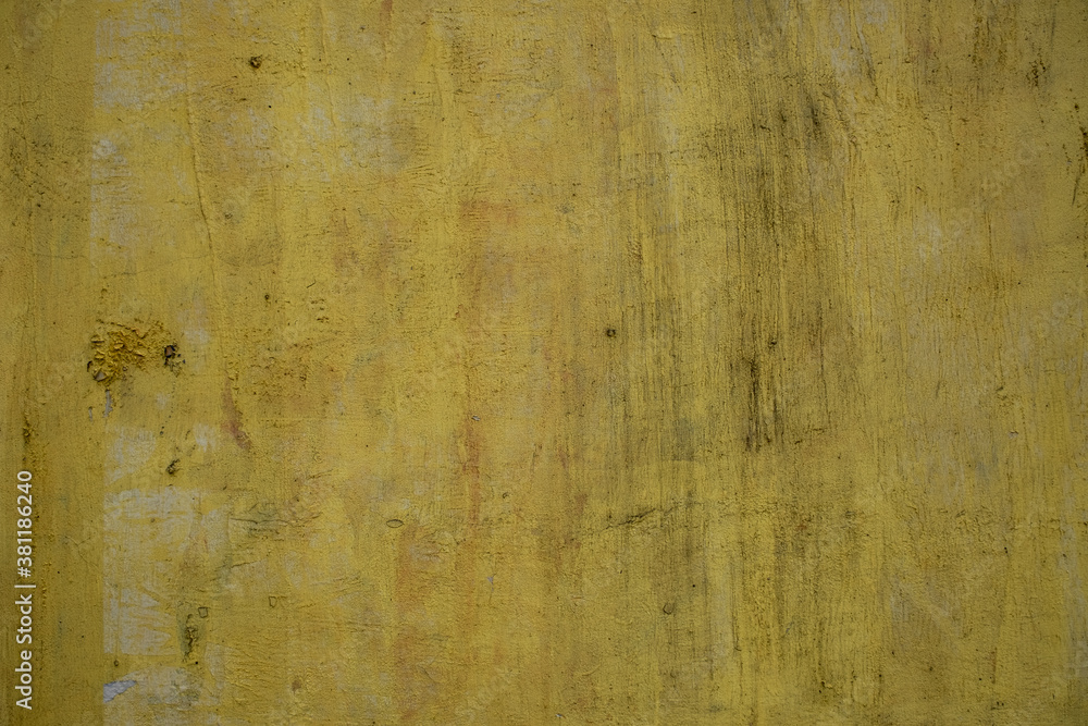 old concrete yellow wall with white paint spots and black scratches. rough surface texture