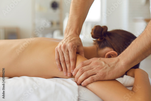Woman lying on massage table enjoying delicate body massage in health clinic or luxury spa salon
