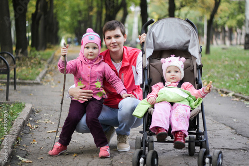 mom walks with two daughters in the autumn park