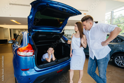 A little boy sits in the trunk while his parents choose a new car © Andrii