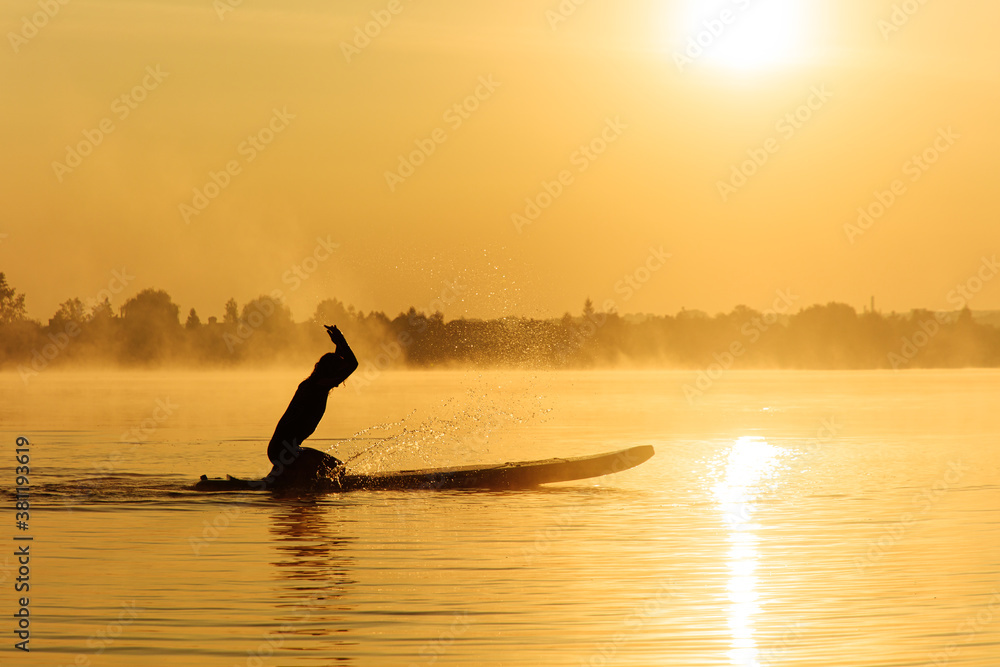 Male surfer splashing water while sitting on paddle board