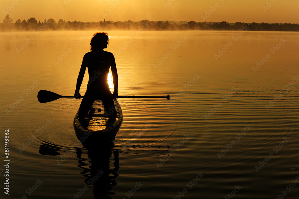 Silhouette of muscular sportsman practicing in sup boarding