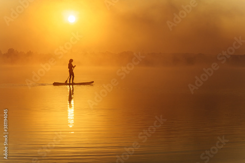 Silhouette of active man standing up on paddle board