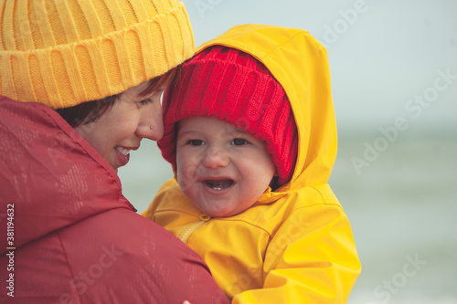Obraz na płótnie Young happy mother with a baby on the seashore in colorful clothes. w salonie