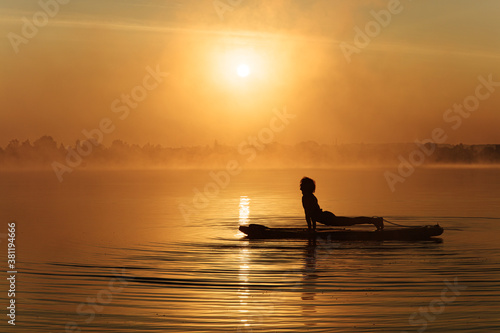 Silhouette of young man stretching body on sup board