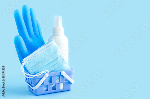 home ordering, personal protective equipment in quarantine. gloves, mask, sanitizer in basket on blue background, copy space, text. delivery, online purchase of medicines. covid-21