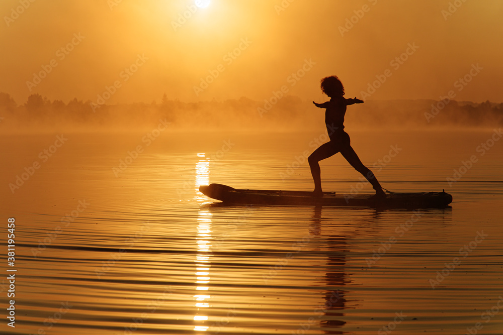Strong young man doing yoga exercises on sup board