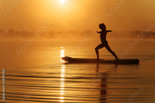 Strong young man doing yoga exercises on sup board photo