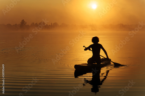 Man in silhouette using paddle for floating on sup board © Tymoshchuk