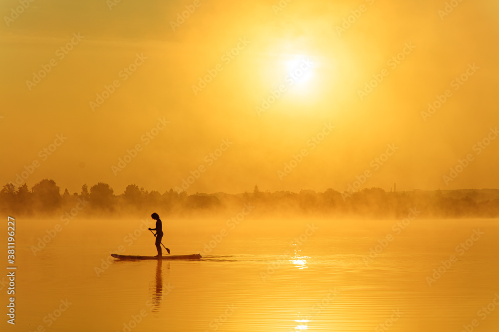 Silhouette of sportive man rowing oar on sup board