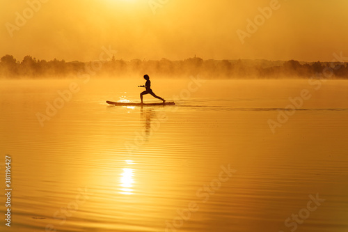 Young man balancing on sup board with paddle in hands © Tymoshchuk