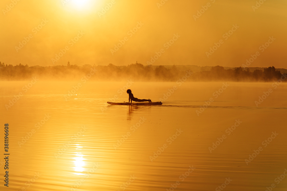 Fototapeta premium Healthy man standing in plank position on paddle board