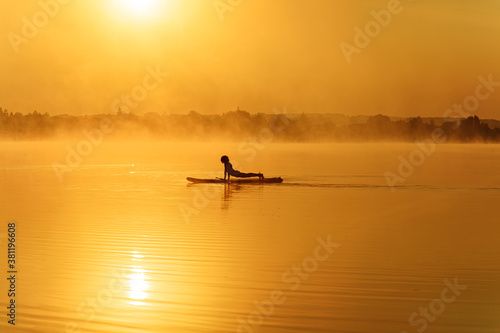 Healthy man standing in plank position on paddle board © Tymoshchuk