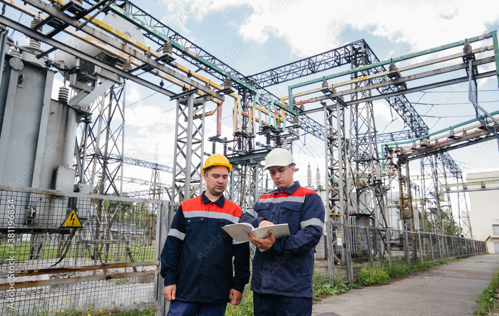 Two specialist electrical substation engineers inspect modern high-voltage equipment. Energy. Industry Two specialist electrical substation engineers inspect modern high-voltage equipment. Energy. Industry