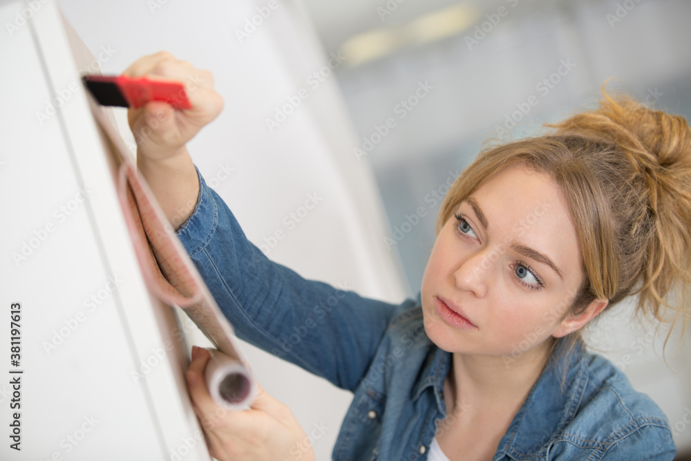 woman unrolling a wall paper on the wall woman unrolling a wall paper on the wall