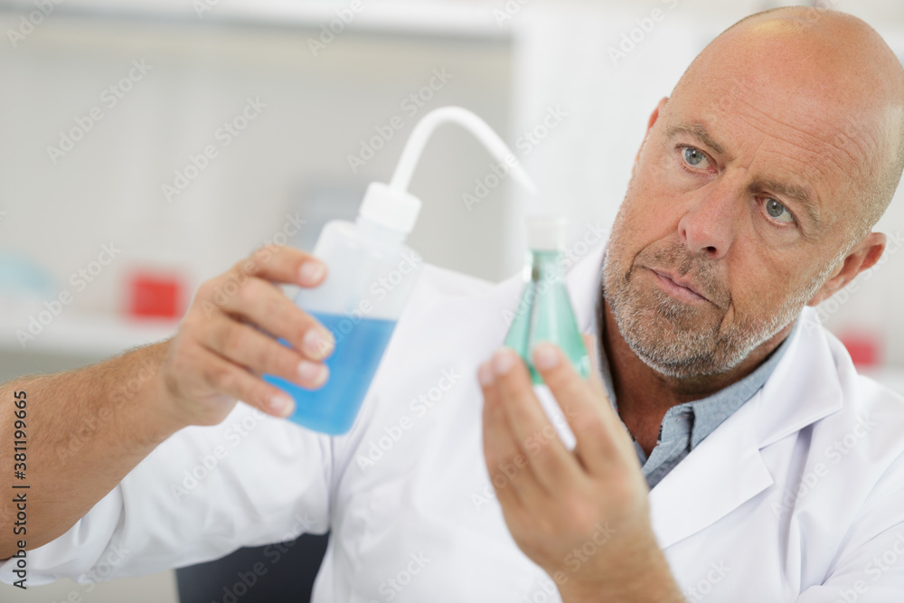 senior scientist dropping liquid into small glass flask