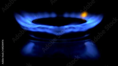 Gas is switching on, apearing blue flame. Gas stove on black background. Slowmo