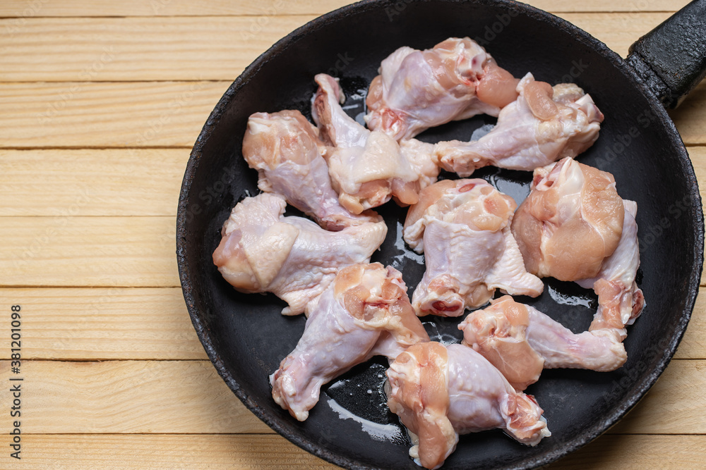 fresh chicken wings at frying pan on a wooden desk. cooking hen wing fresh chicken wings at frying pan on a wooden desk. cooking hen wing
