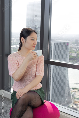 Young Chinese woman having coffee by the window