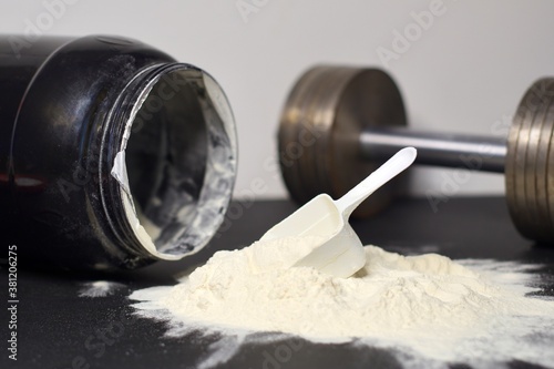 Scoop of whey protein, sports supplement, nutrition for gain muscles, dumbbell and a container