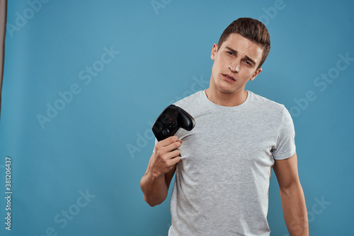 A man with a joystick in his hands entertainment leisure technology video games blue background white t-shirt
