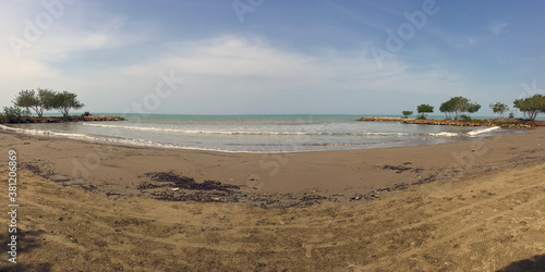 Dirty Beach with some Debris in the Sand  with some Trees on the Edges and a Wonderful View of the Turquoise Sea on a Sunny Day in Santiago de Tol    Colombia